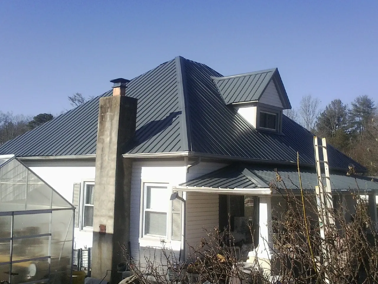 Dark blue standing seam metal roof on a white farmhouse with dormer — Slate & Tile Roof Repair by Roofing Brothers in Morrison