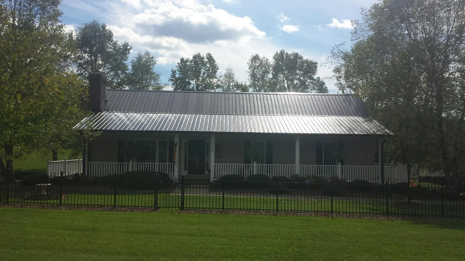 Gray metal roof on a brick ranch with a full width front porch — Gutter Guard Installation work by our crew in Morrison